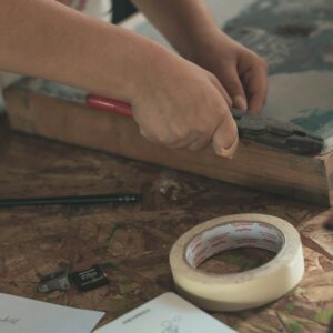 person holding pliers near adhesive tape